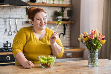 Fat obese plump young caucasian woman eating salad for healthy diet and eating habits in the...
