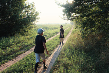 Small children play catch-up and run along a beautiful green road. Happy childhood.