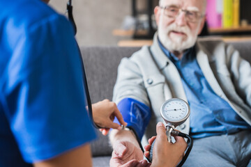 Cropped close up photo of a health female visitor measuring a blood pressure of a senior grandpa man at home. Elderly hypertension cardiovascular problems concept.