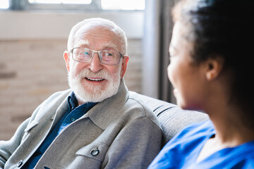 Senior elderly old caucasian man asking young african doctor about indications and contraindications of new medicine, healthcare and medicine concept.