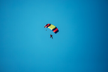 a skydiver descends to the ground from the sky in clear weather. extreme sports to overcome the...