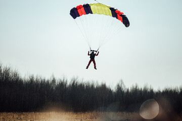 a skydiver descends to the ground from the sky in clear weather. extreme sports to overcome the...
