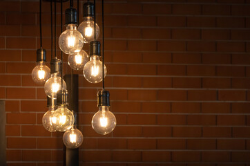 vintage light bulbs are hanging from ceiling for decoration in living room with red brick background.