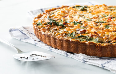 Close up view of a freshly baked quiche on a kitchen towel ready for serving.