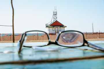Lost and broken prescription eye glasses sit on a picnic table with the Leuty Lifguard Station building in the background in Toronto’s Beaches neighbourhood.