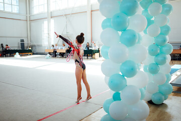 the gymnast girl demonstrates flexibility and dexterity in the gym at competitions in front of the...