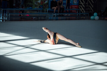 the gymnast girl demonstrates flexibility and dexterity in the gym at competitions in front of the...
