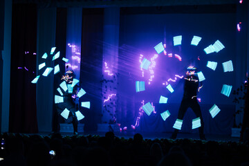 light show in LED suits. the artists on the stage dance beautifully with bright multicolored...