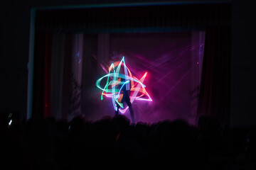 digital art dance show in LED costumes. neon fans in the hands of artists dancing in the dark on...