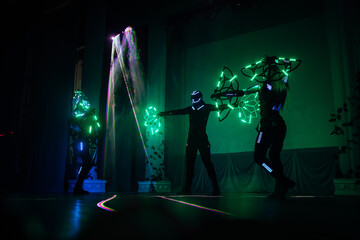 digital art dance show in LED costumes. neon fans in the hands of artists dancing in the dark on stage