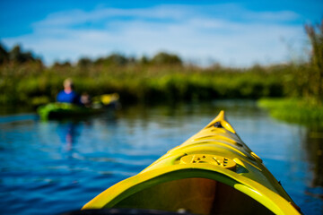 The front of a green kayak overlooking a river in the forest 