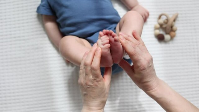 close-up high angle view hands doing exercises with infant baby legs and feet