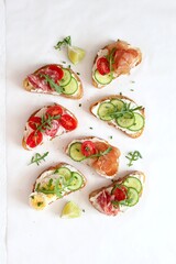 Variety of sandwiches with light cheese, vegetables and salami on light background. Top view.