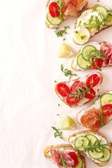 Variety of sandwiches with light cheese, vegetables and salami on light background. Top view.