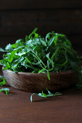 Fresh arugula leaves in a wooden bowl. Top view with copy space.