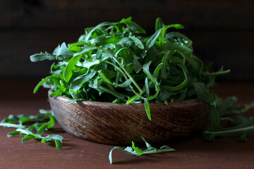 Fresh arugula leaves in a wooden bowl. Top view with copy space.