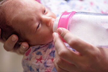 Mother feeds the newborn with bottle of milk