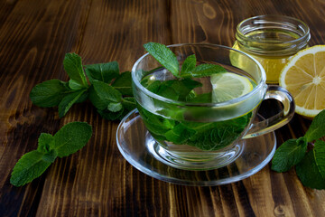 Mint tea in the glass cup on the wooden background. Healthy drink. Close-up.