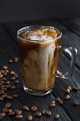 Cold brew coffee with milk in the glass cup on the black  background. Location vertical.