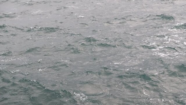 Sea splashes, waves with foam. Water waves surface, background with copy space. Close-up of waving water surface of sea. Water ripple. Sea surface. Ocean wave. 