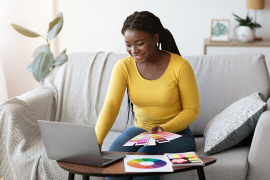 Black woman interior designer working with color swatches and laptop at home