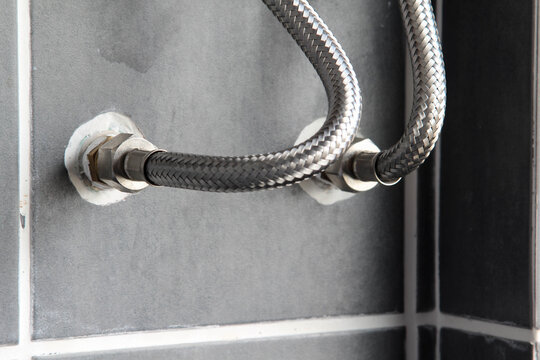 Connecting the inlet hose to the water supply pipe in the wall.