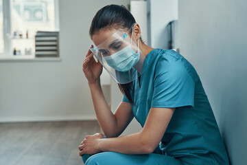 Overworked young female nurse in protective workwear 