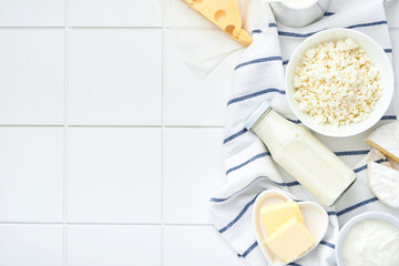 Glass of milk, cottage cheese, ricotta, sour cream, cheese, camembert and butter on white table background. Different dairy products. Milk concept. Top view with copy space. Mock up.