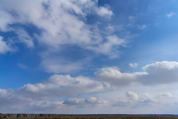 The sky is deep blue with many floating cumulus clouds. View of a beautiful sky with white clouds without any objects. The texture of the blue and white sky. Serene sky on a sunny day