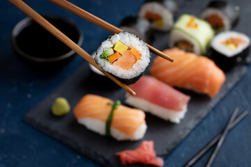 Eating Sushi with chopsticks. Sushi roll japanese food in restaurant. Sushi roll set with salmon and vegetables.Close up. Japan restaurant menu.