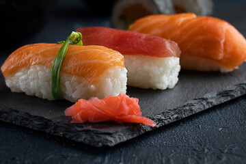 Rainbow Sushi nigiri with salmon, tuna and vegetables placed on black rock.Japan restaurant menu.Close up.