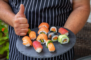 Closeup of master chef holding food tray with sushi pieces. Concept of food preparation, ready for product placement.Japan restaurant menu.