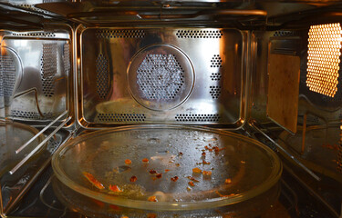 Oil and foods residue on glass turntable inside a dirty microwave