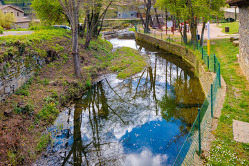 Reflections in the water of the Rupit stream as it passes the medieval nucleus. Rupit, Catalonia, Spain