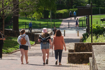 Female college students wearing protective face masks walk across campus. 