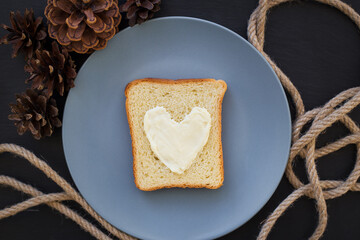 sandwich for breakfast in form of heart with cheese on a blue plate and black background with cones