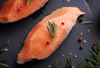 Fresh fish. piece of raw salmon fish fillet, spices on a black stone surface, Delicious fish meat. top view. Healthy food.