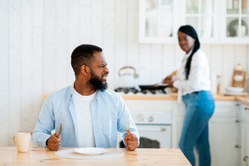 Impatient Hungry Black Husband Waiting For Food, Sitting At Table In Kitchen