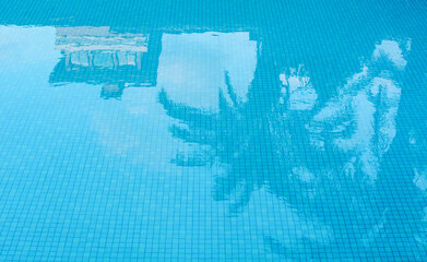 Reflection of the hotel and palm trees in the swimming pool.