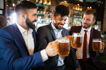 Meeting with the best friends. Happy young business men talking and drinking beer in a pub