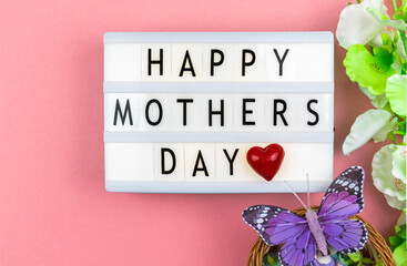 Happy Mother's Day text greeting card, love pink background with red heart and spring flowers, flat lay and top view