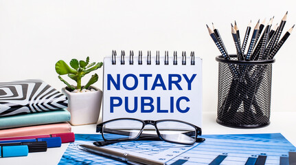 Against the background of a blue scheme and a white wall, black pencils in a stand, a flower, diaries and a notebook with the inscription NOTARY PUBLIC