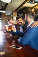 Group of happy friends drinking beer at the pub and having fun