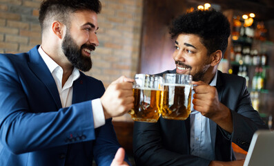 People, friendship and celebration concept. Happy business male friends drinking beer at pub
