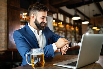 Handsome young business man, blogger or remote working with laptop in bar