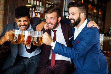 Young businessmen are drinking beer, talking and smiling while resting at the pub