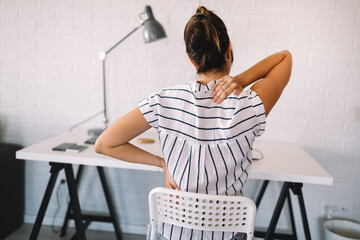 Overworked woman with back pain in office with bad posture