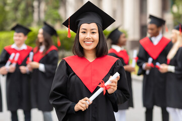 Happy asian woman student cheerfully posing while graduation ceremony