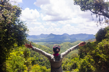 A women standing on cliff and see over view in nature.Tourist show  hands up and enjoying fresh air. A women enjoying free happiness in beautiful Thailand landscape.