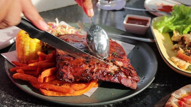 Cutting a piece of a Grilled and barbecue ribs pork with a knife.